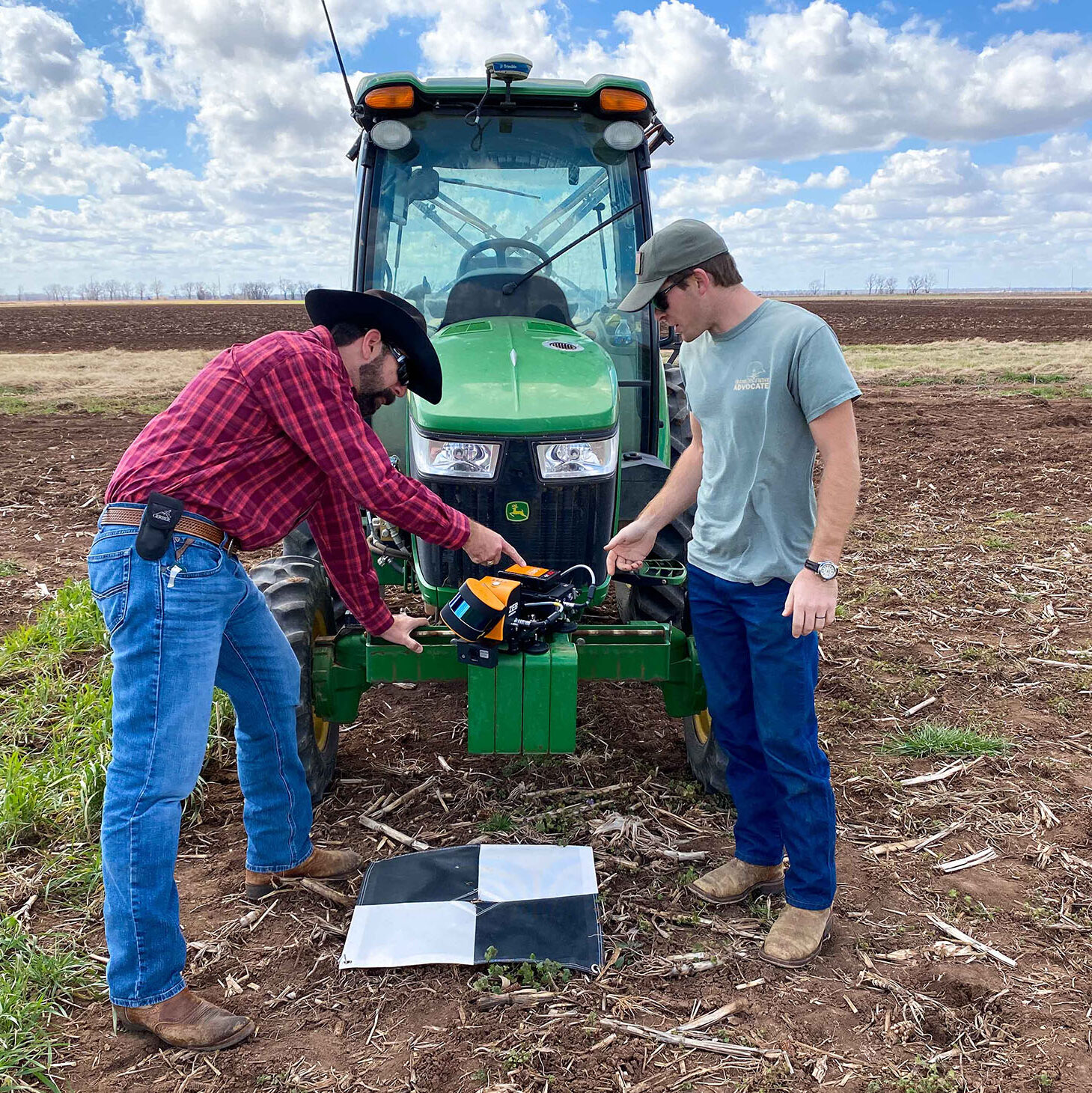 Field Work, to men looking at a tractor on a field.
