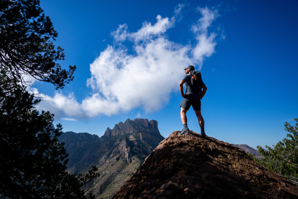 Man standing on top of a hill while looking out onto a scenic view.