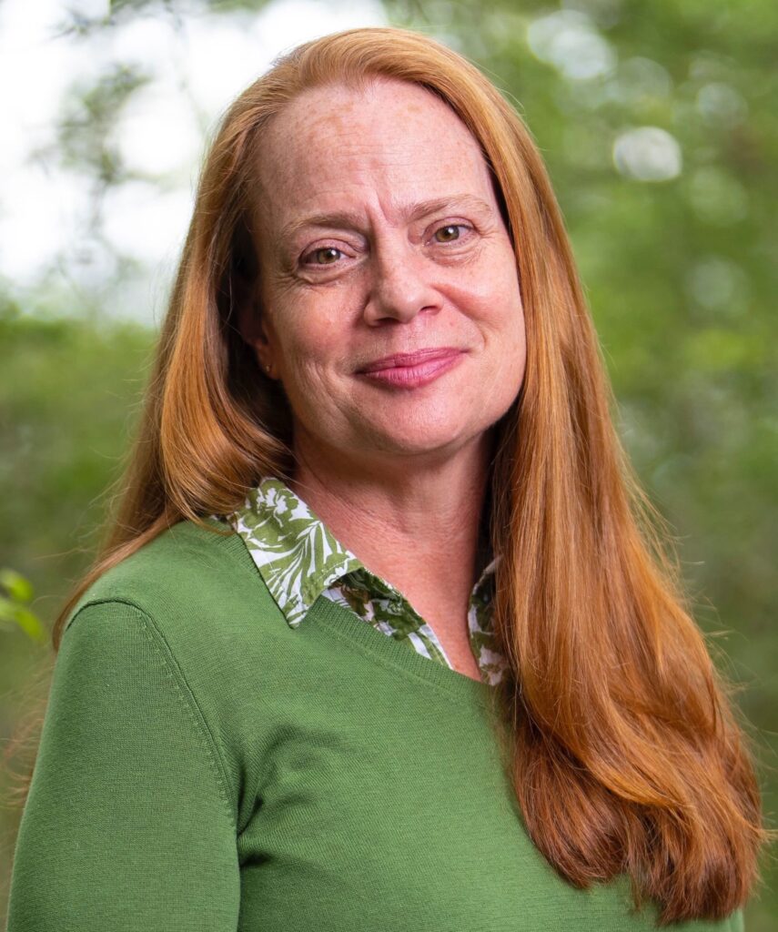 Katy Gonder outdoors with greenery in background.