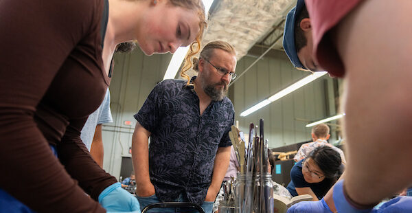 Man teaches class as three students work on their ecology projects on trays.